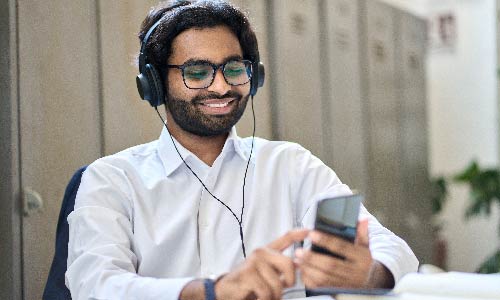 man wearing headphones scrolls on his phone