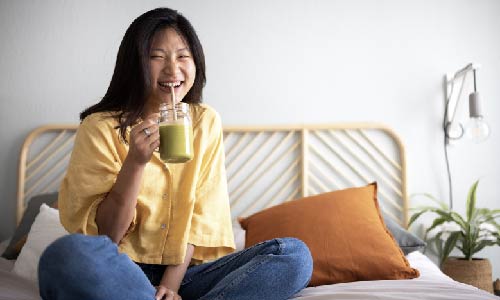smiling young woman drinking green smoothie