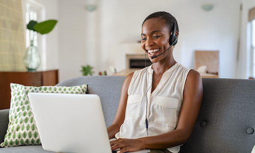 smiling woman working an a laptop while talking on a headset
