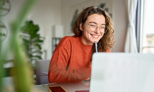 smiling woman taking a training course on a laptop computer