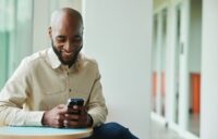 smiling man taking compliance training on his phone