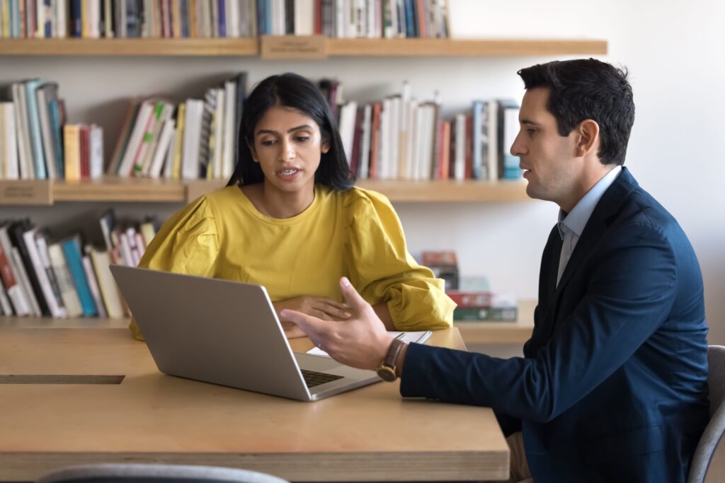 Two employees discussing feedback in front of a laptop.