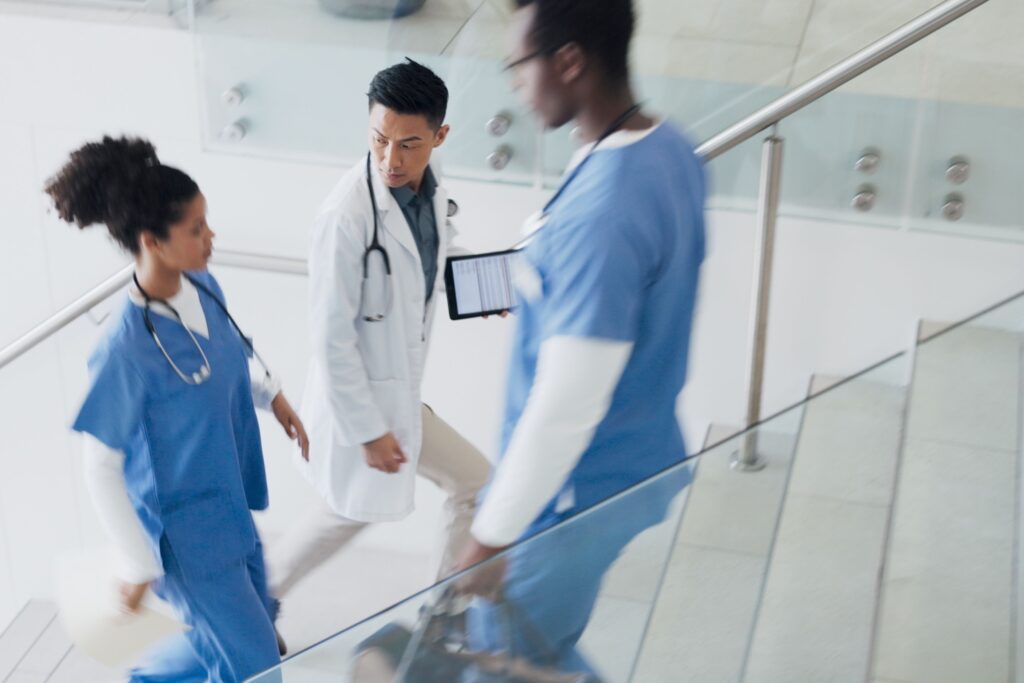 Doctors, nurses, and physicians assistants hurrying down the stairs of a busy hospital.