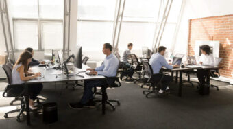 office with workers sitting at tables on computers