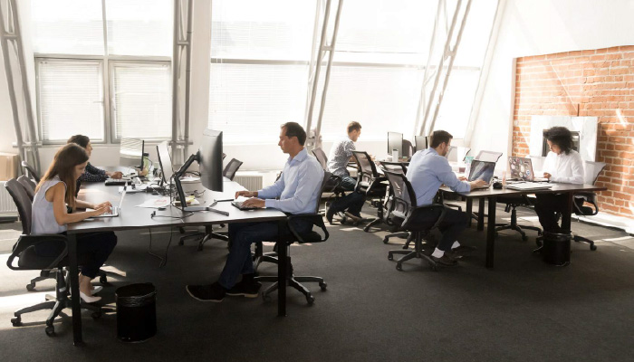 office with workers sitting at tables on computers
