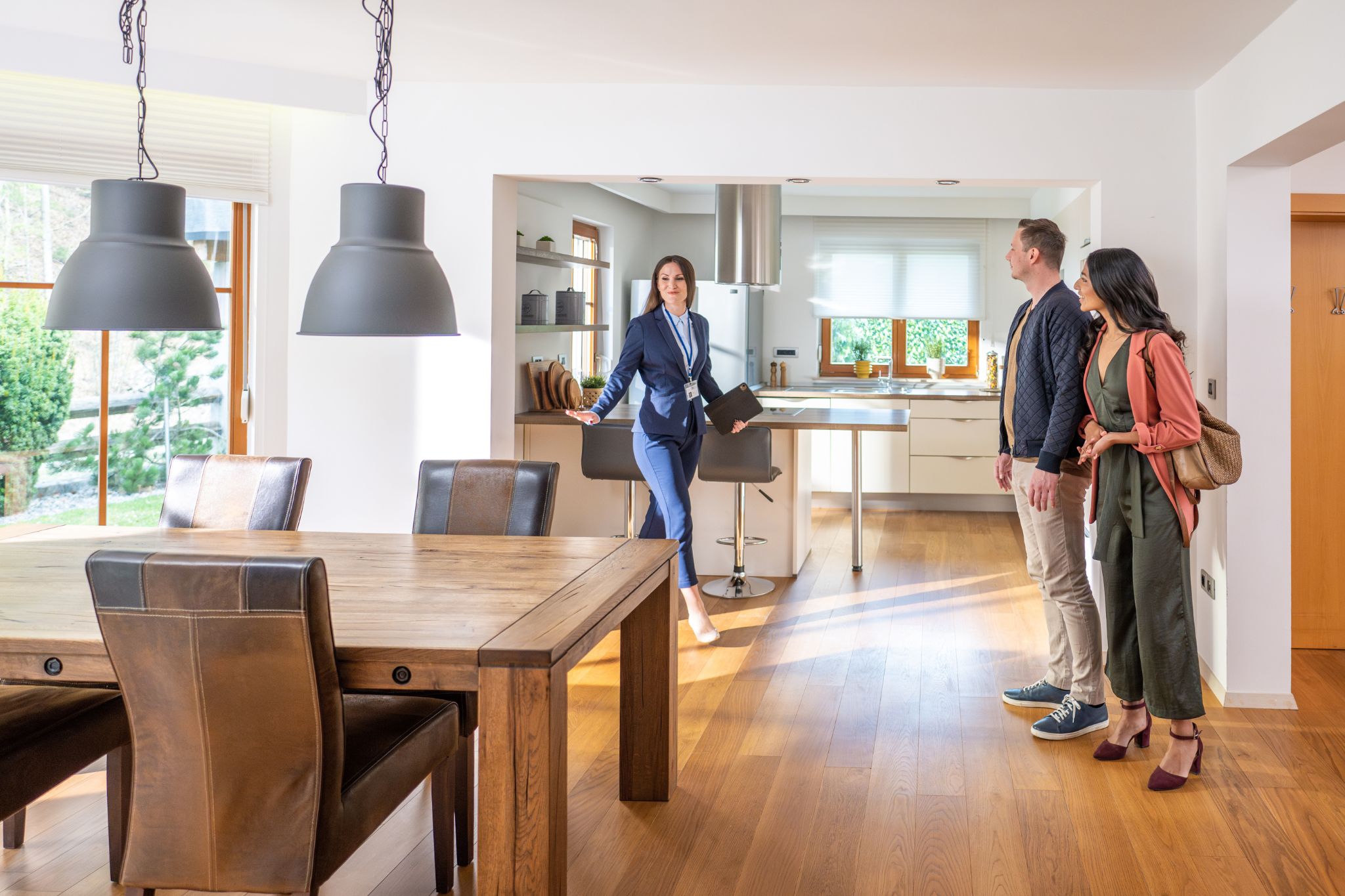 Female real estate agent shows a home to a couple. Global Real Estate School builds a successful online real estate training program with their learning management system.