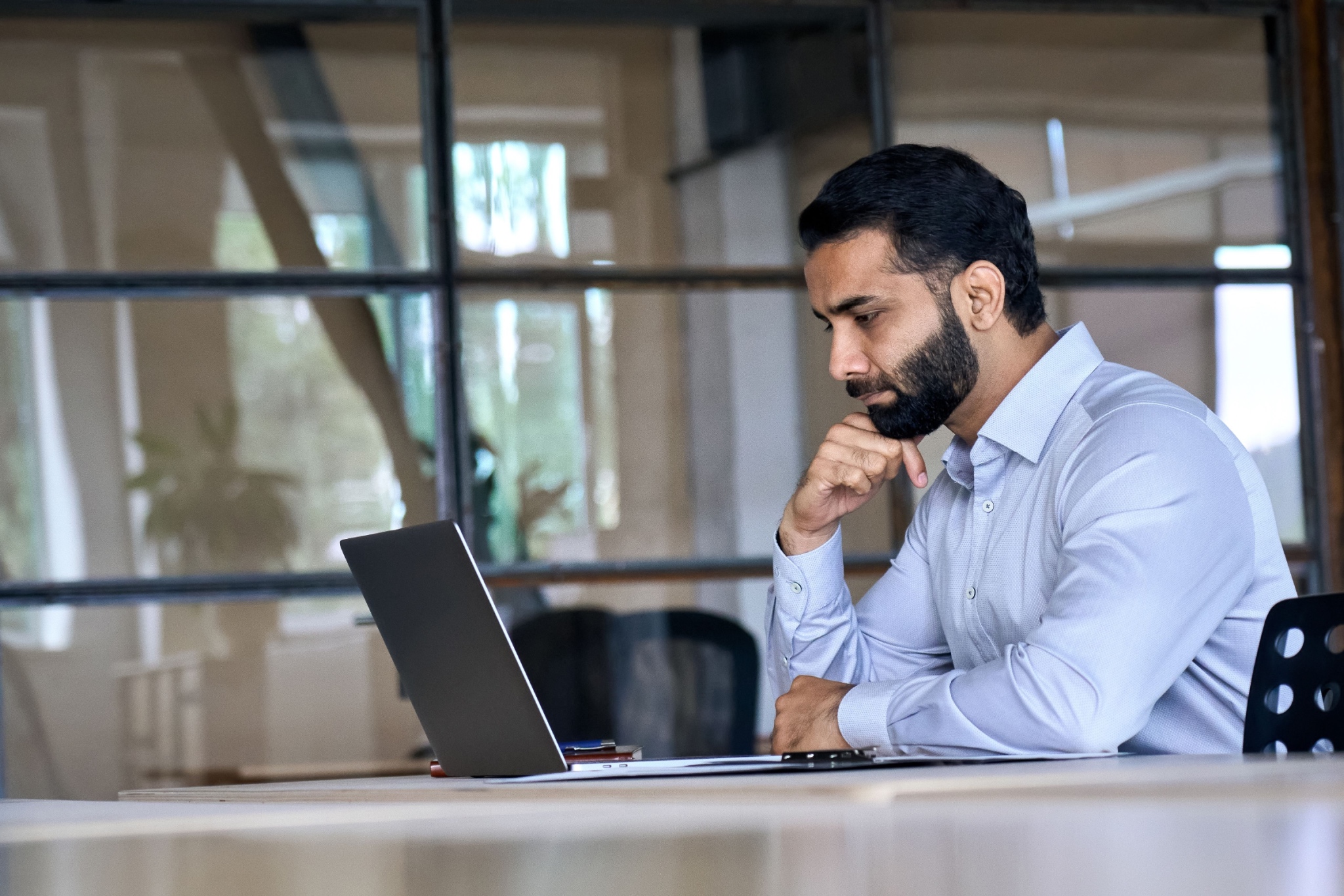 Corporate professional using a laptop in an office.