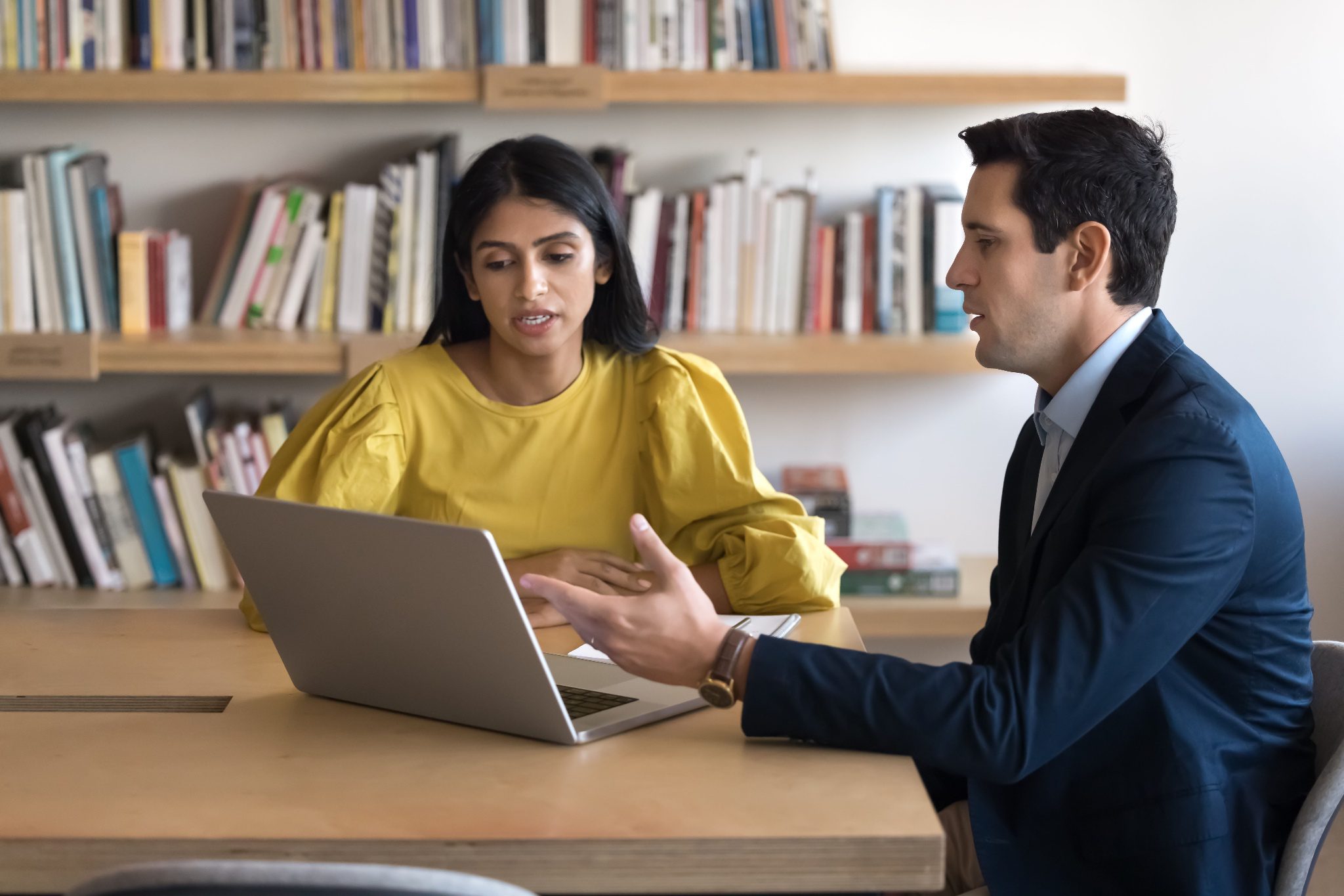 Two employees discussing feedback in front of a laptop.