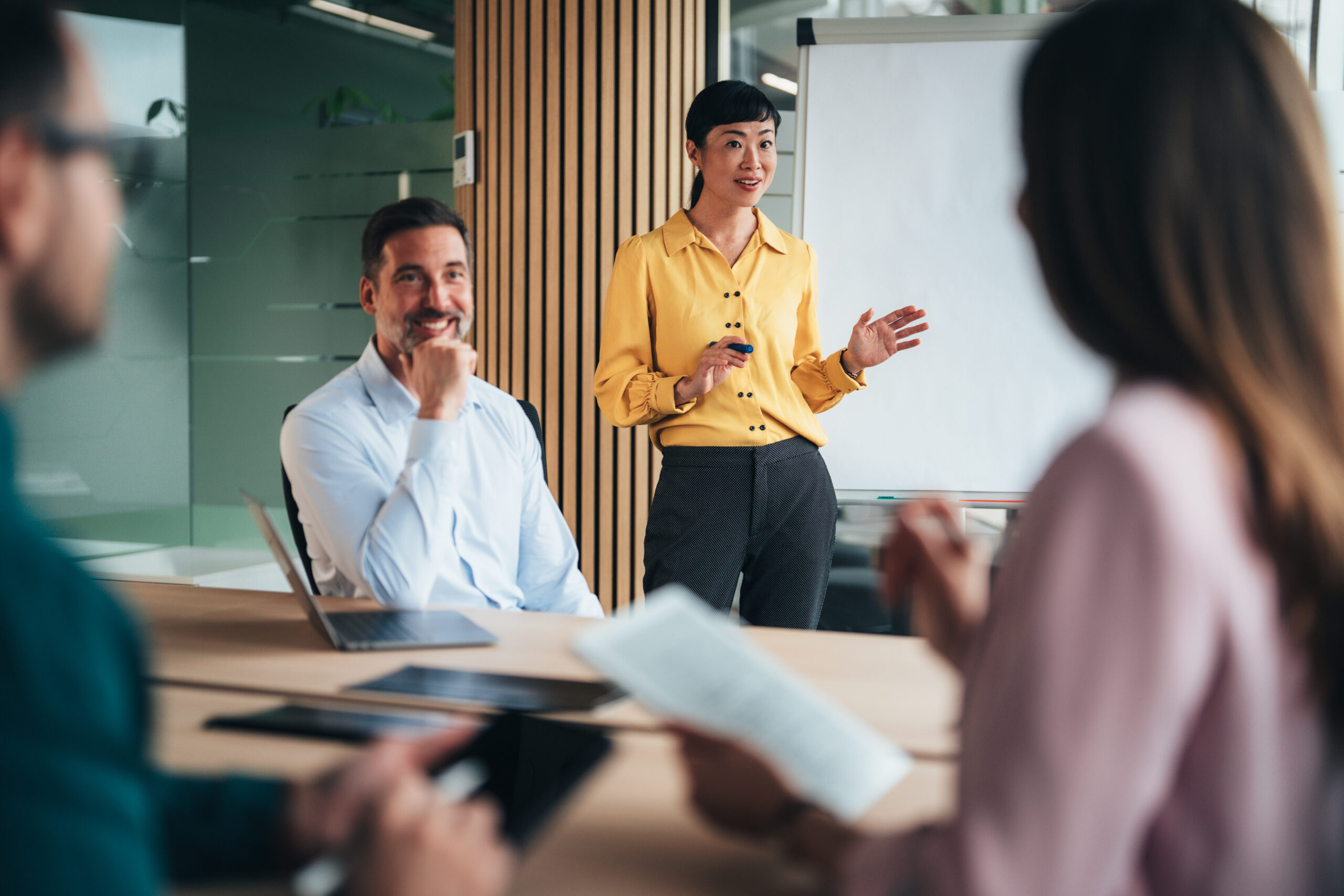 A team of business professionals take part in an active meeting, exchanging training ideas and reviewing plans for implementing L&D programs, in a modern office environment